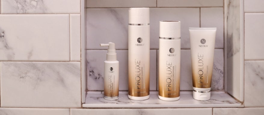  Image of the ProLuxe Hair Care System, including Scalp Treatment, Hair Mask, Conditioner and Shampoo in a shower niche. 