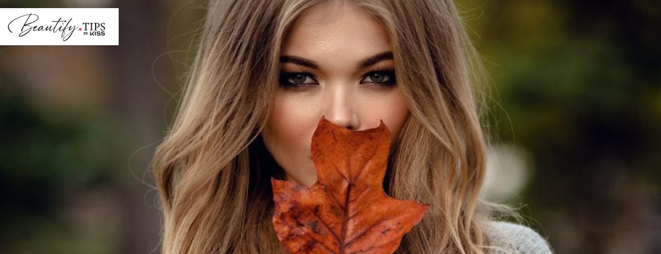 Image of a woman holding a vibrant fall leaf. 