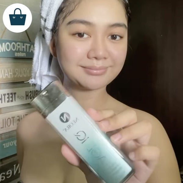 A woman holding a bottle of Age IQ Day Cream.