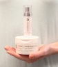 A hand holding a container of Neora’s  Complexion Clearing Pads with a bottle of Neora’s IllumaBoost on top.