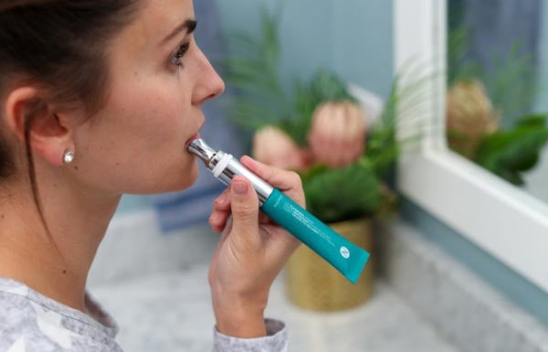 A woman applying the Lip Plumping Serum in the bathroom.