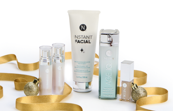 Neora’s IllumaBoost, Instant Facial, Age IQ Day Cream, and Shimmer Lip Oil surrounded by gold ribbon and ornaments. Accompanying text states “FREE Gift!” and “Holiday Exclusive.”