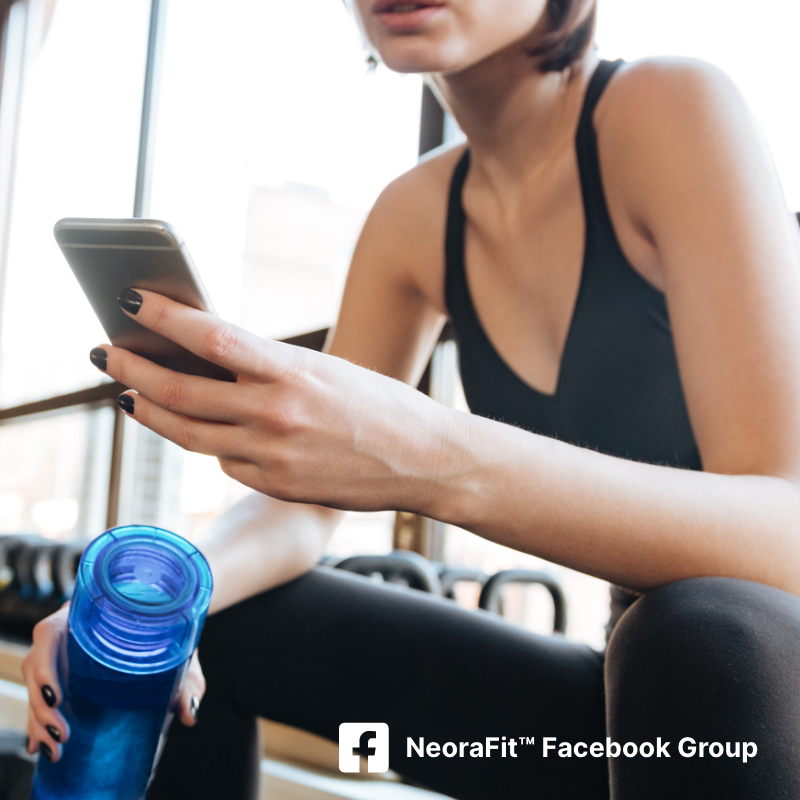 A woman in fitness attire sitting down with her phone and water bottle in hand.