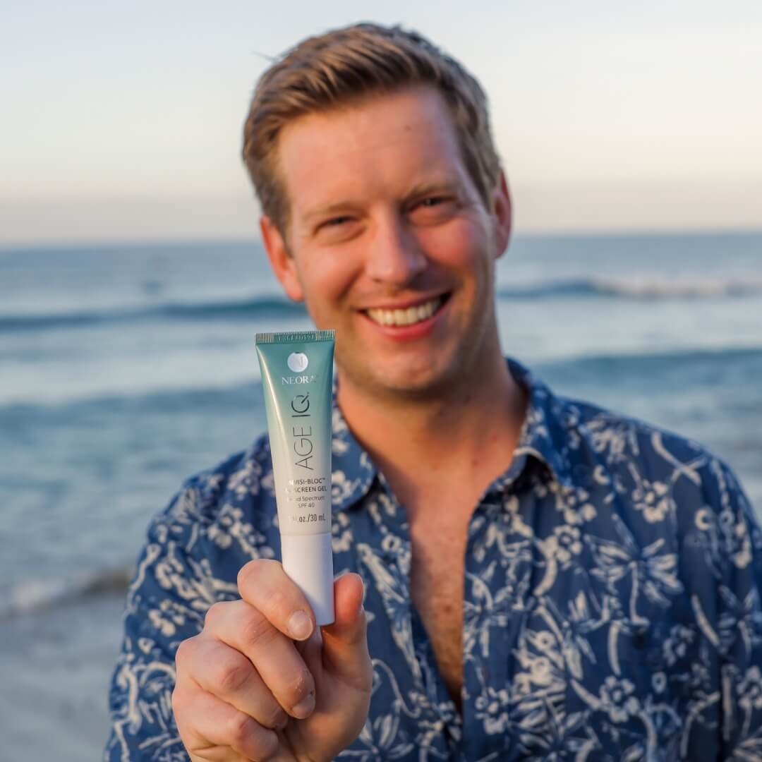 A man holding up a bottle of Neora's Invisi-Bloc SPF.