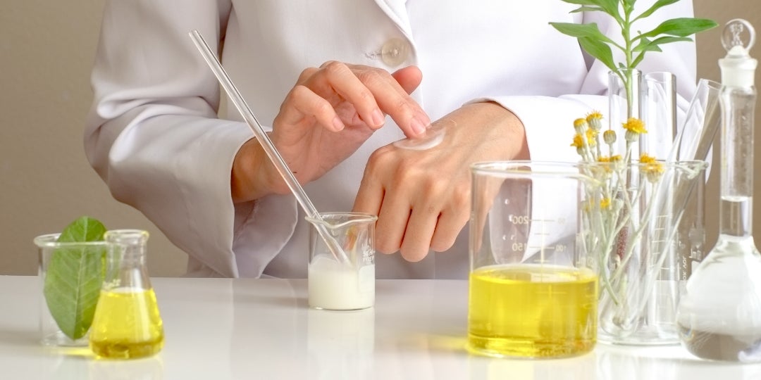 A scientist testing ingredients from beakers.