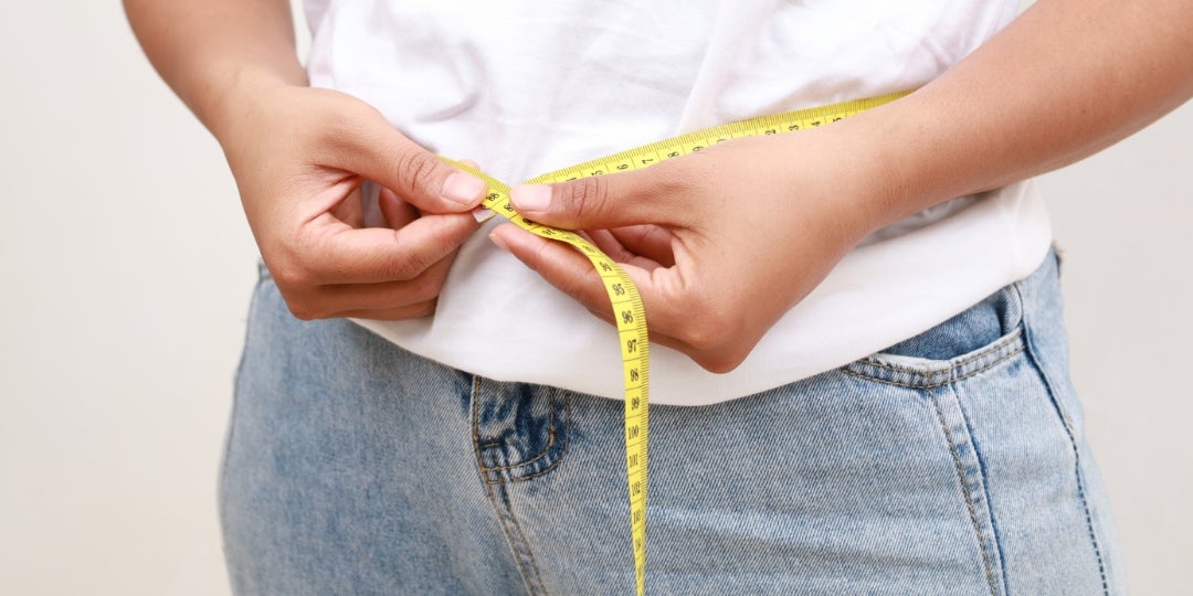 A person using a tape measurer around their waist.