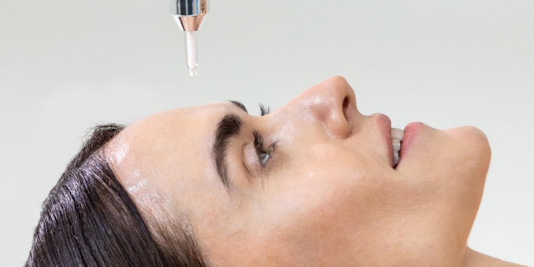 A woman applying a Neora product to her forehead.