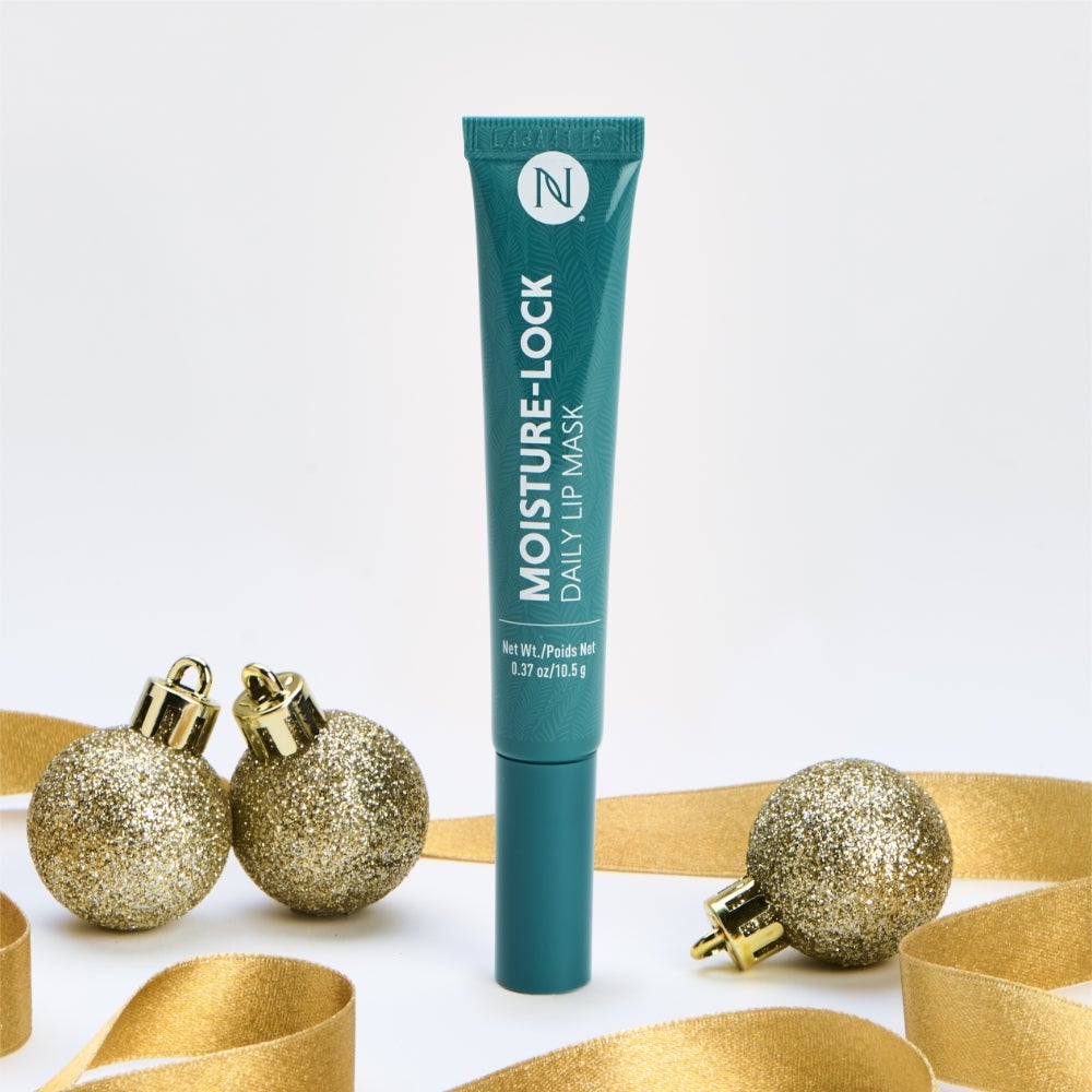 Neora’s Moisture-Lock Lip Mask tube surrounded by gold ribbon and ornaments.