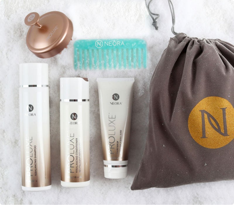 El juego navideño imprescindible de Neora, Get-Gorgeous Holiday Hair Set, que incluye Champú equilibrante ProLuxe™, Acondicionador equilibrante ProLuxe™, Mascarilla para el cabello ProLuxe™, Peine desenredante GRATIS + Depurador de cuero cabelludo GRATIS y Bolsa de regalo GRATIS sobre un lecho de nieve.