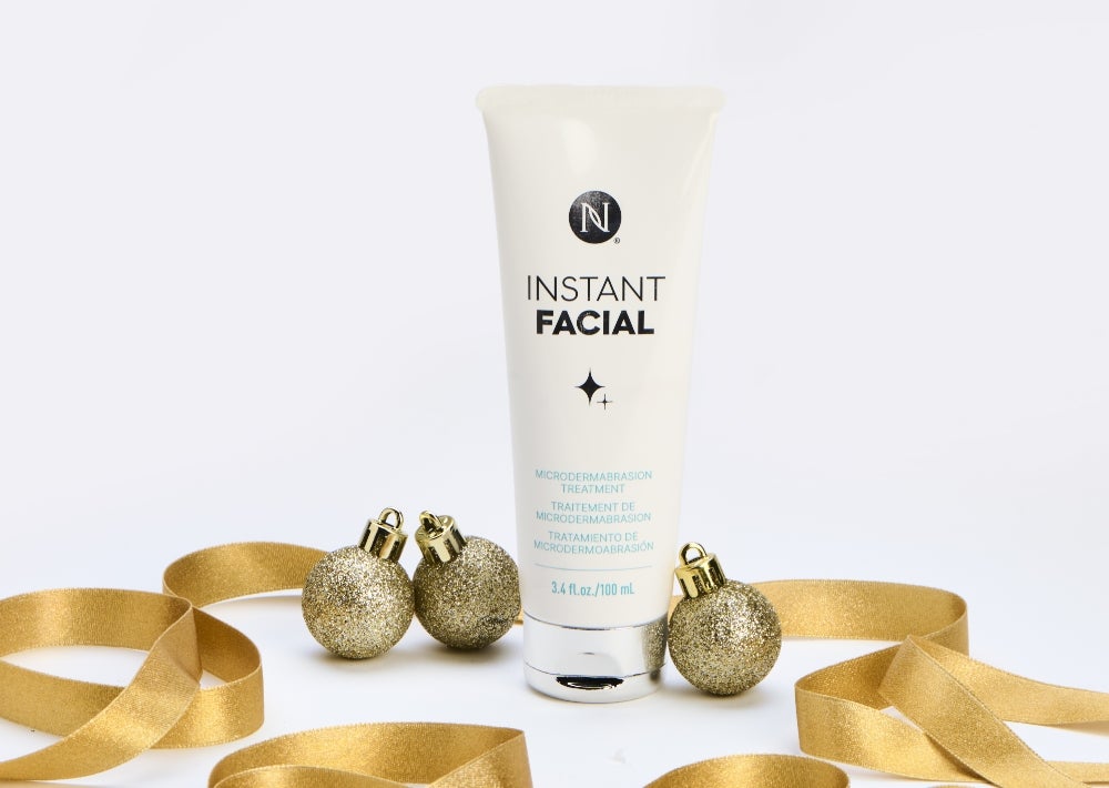 New limited-edition Instant Facial Microdermabrasion treatment. Achieve flawlessly smooth and clear skin for $188 retail or $155 with SmartShop. Background imagery includes a Neora Instant Facial tube surrounded by gold ribbon and ornaments.