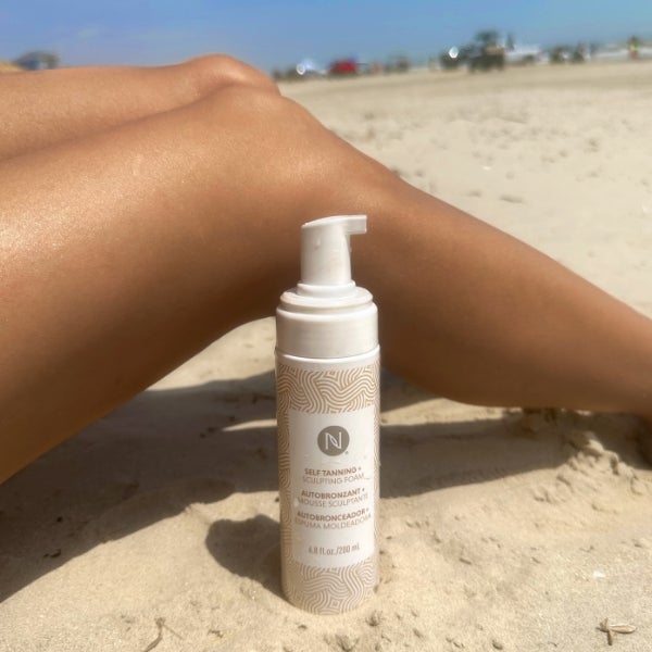 Photo collage showing a bikini-clad woman posing with the 3-in-1 Self Tanning and Sculpting Foam, sunkissed legs on a beach with the product bottle, and the product on a beautiful, wave-lapped beach.