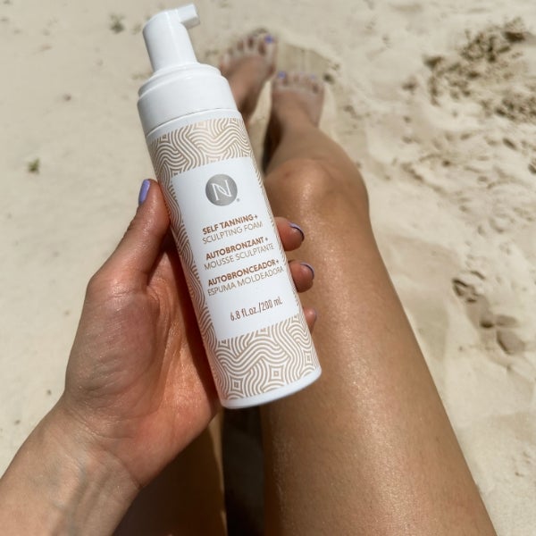 Photo collage showing a bikini-clad woman posing with the 3-in-1 Self Tanning and Sculpting Foam, sunkissed legs on a beach with the product bottle, and the product on a beautiful, wave-lapped beach.